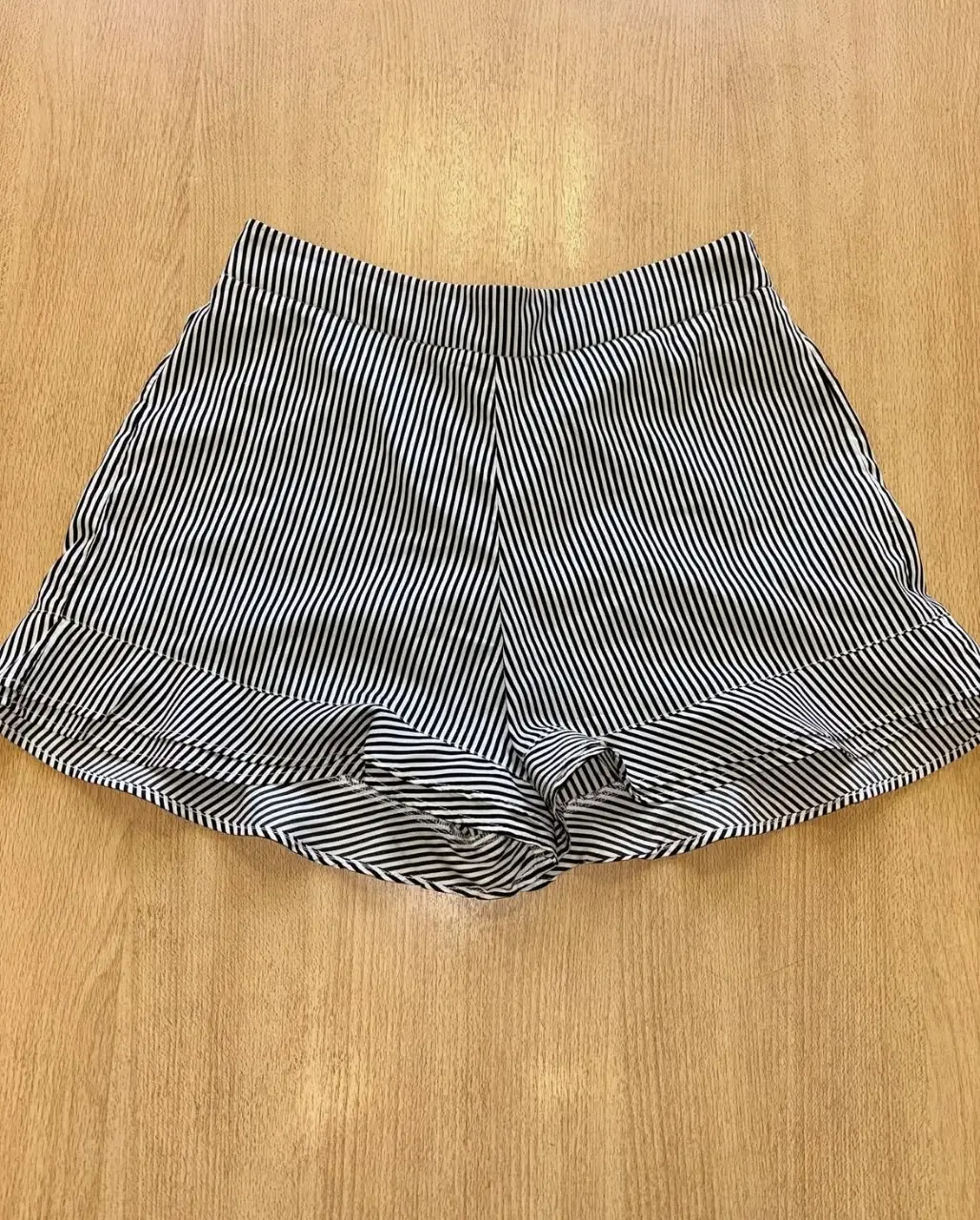 Shorts de mujer a rayas verticales en blanco y negro. Talle 1, con cintura elastizada y detalle de volados en el borde inferior. Ideal para un look casual y fresco.