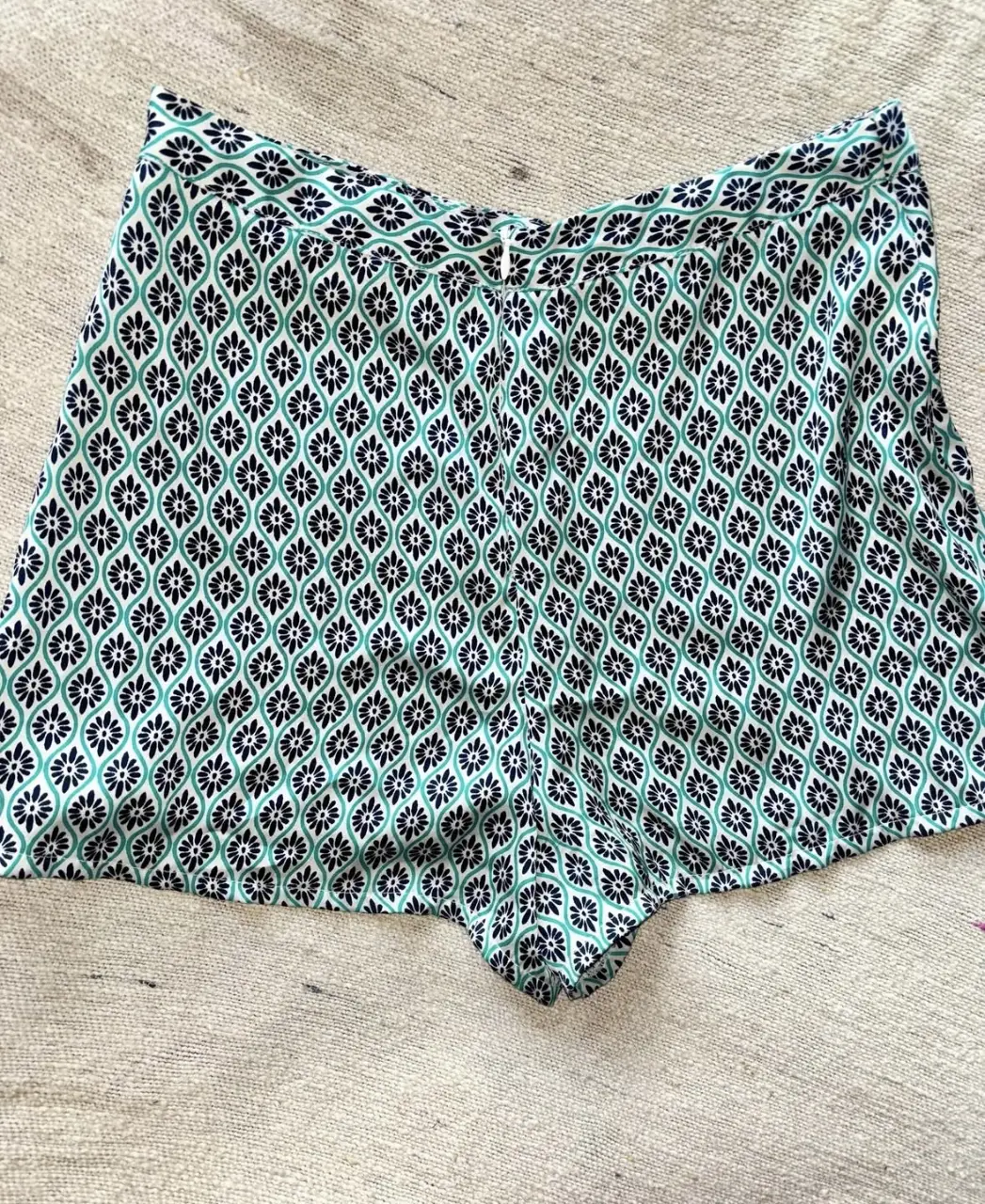 Shorts de tela con estampado floral en tonos verde y negro. Ideal para un look fresco y moderno.