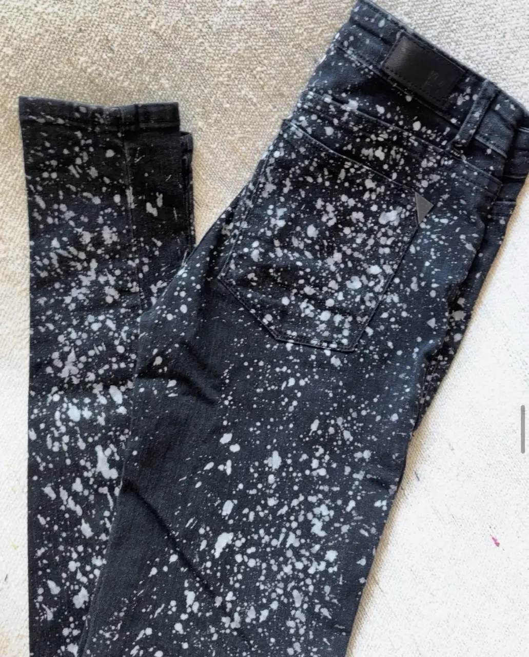 Jeans negro con salpicaduras blancas, tiro medio y corte recto. Un clásico con un toque moderno para un look canchero.