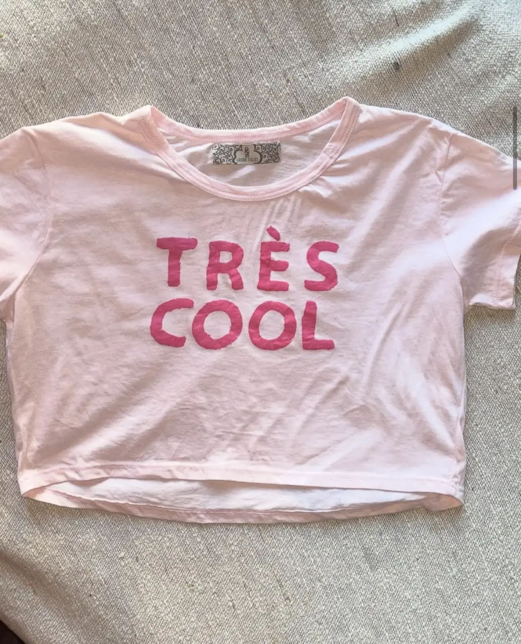 Remera crop top rosa claro con estampado "TRÈS COOL" en rosa. De la marca Laura Felici, ideal para un look casual y moderno.