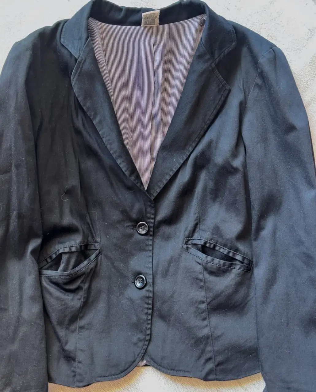 Blazer negro de mujer, con forro a rayas. Ideal para un look formal o de trabajo.