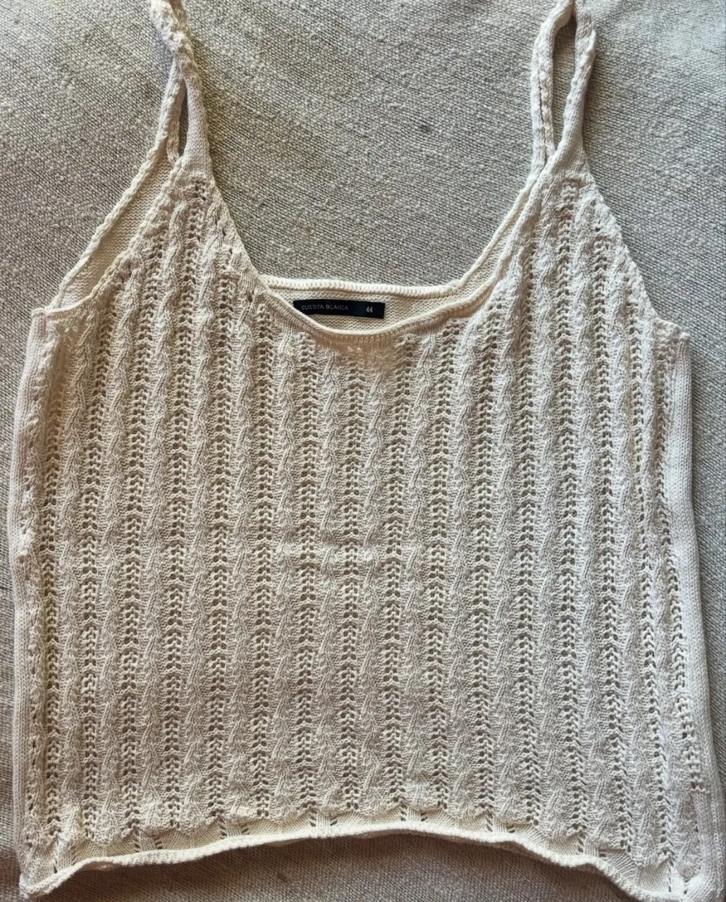 Top tejido de mujer, color crudo, con tirantes finos y detalle calado. Ideal para un look casual y fresco.