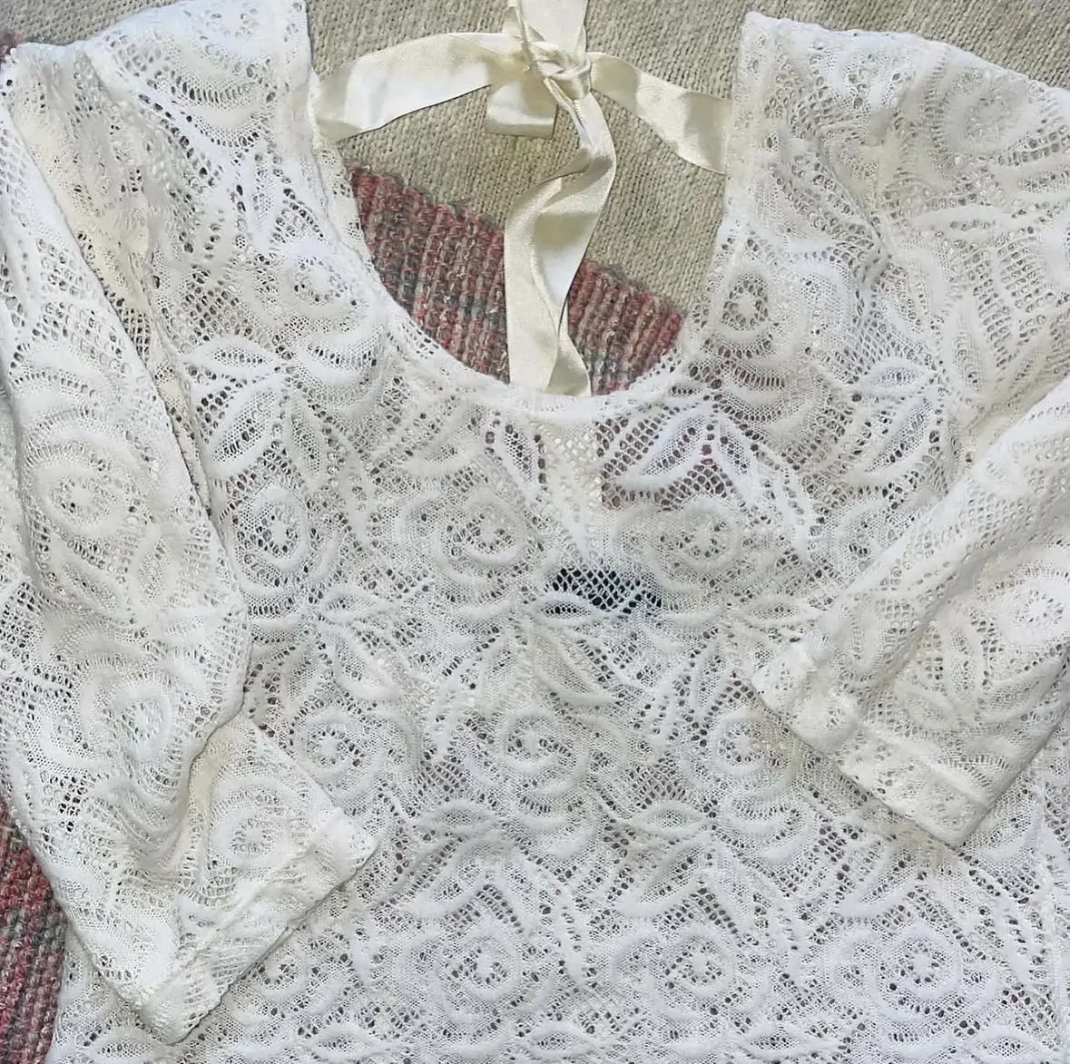 Blusa de encaje blanco, con mangas largas y detalle de lazo en la espalda. Ideal para un look romántico y elegante.