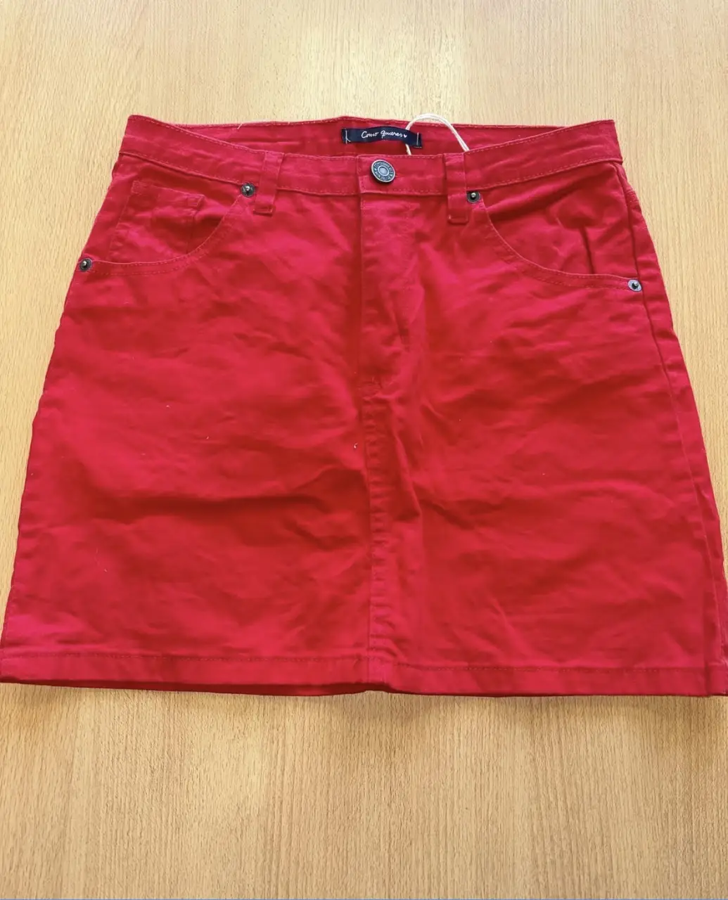 Minifalda roja de jean, tiro medio, con bolsillos delanteros y traseros. Ideal para un look casual y moderno.