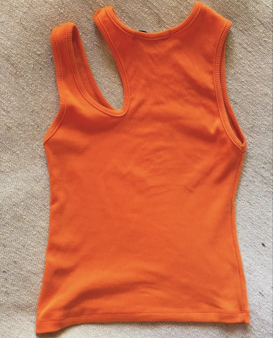 Musculosa naranja con un diseño asimétrico en el cuello. Ideal para un look moderno y fresco.