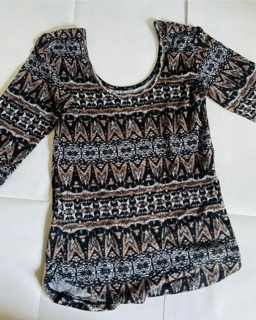 Blusa de mujer con estampado geométrico en tonos marrones y negros. Cuello redondo y mangas 3/4. Ideal para un look casual y cómodo.