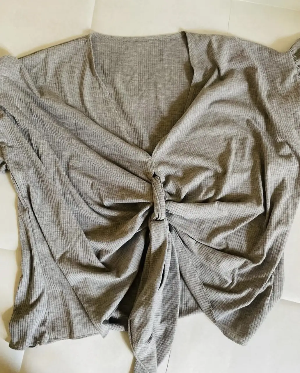 Blusa gris con detalle anudado en el frente y mangas cortas. Ideal para un look casual y moderno.