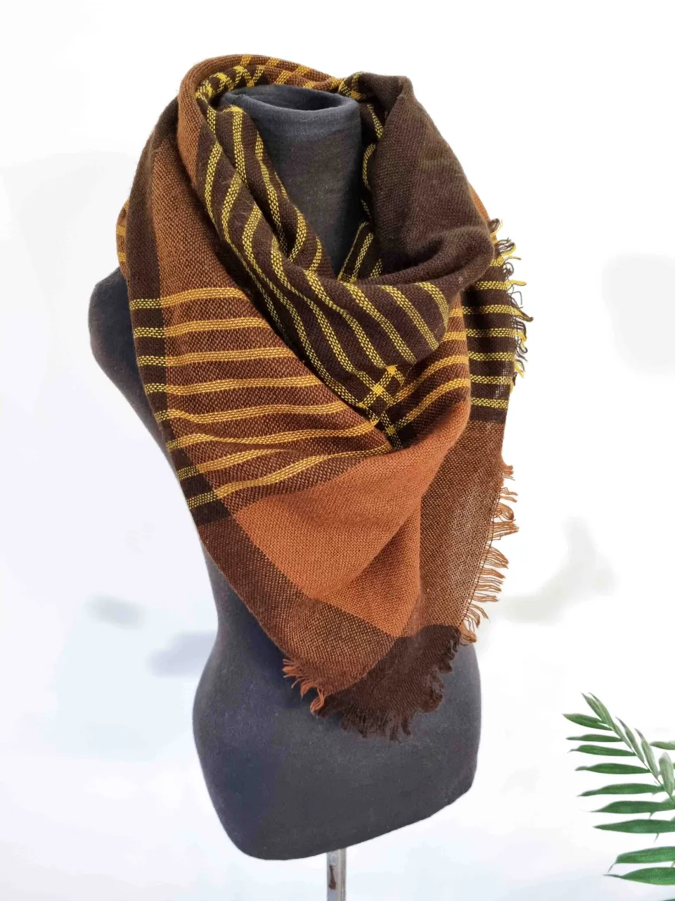 Bufanda de cuadros escoceses en tonos marrones y amarillos. Posee flecos en los bordes. Medida 112x112 cm.