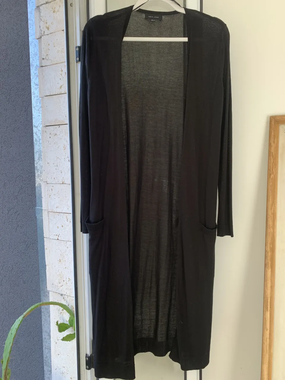 Cardigan largo de hilo color negro, con bolsillos delanteros.