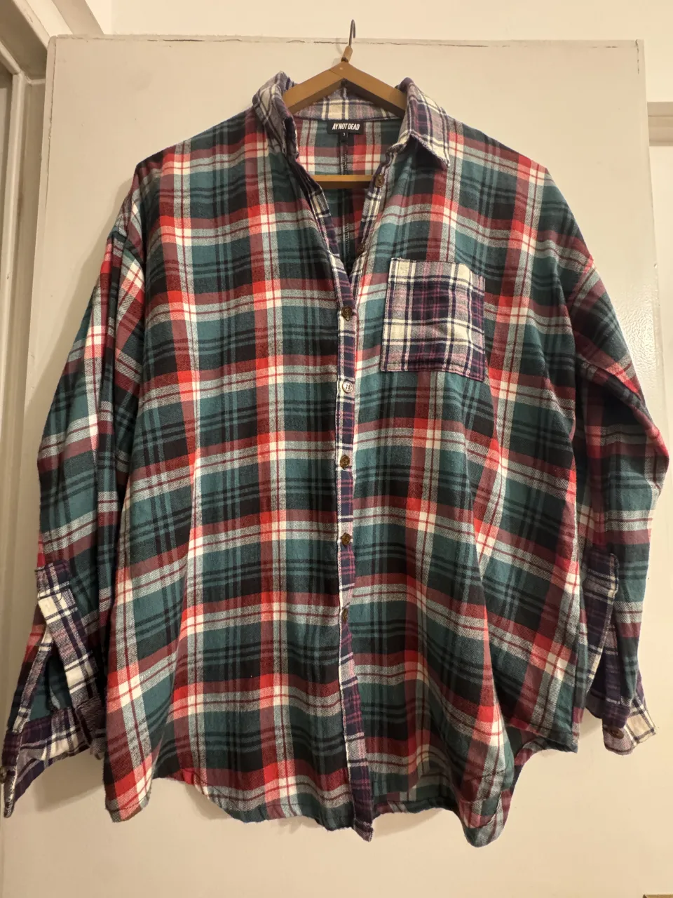 Camisa de lanilla a cuadros de manga larga con botones al frente y bolsillo en el pecho.