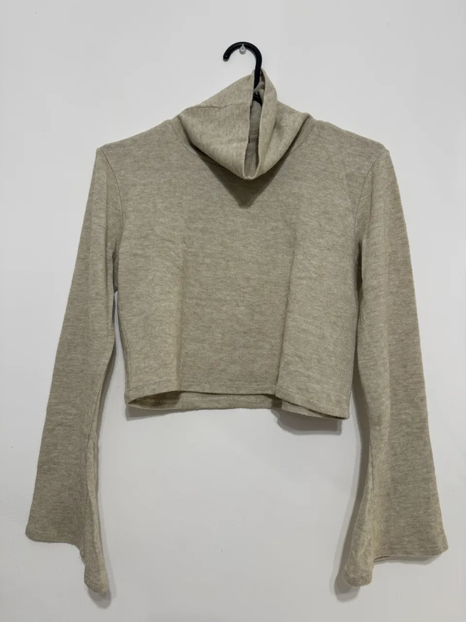 Sweater crop de lanilla manga larga con cuello alto y mangas acampanadas.