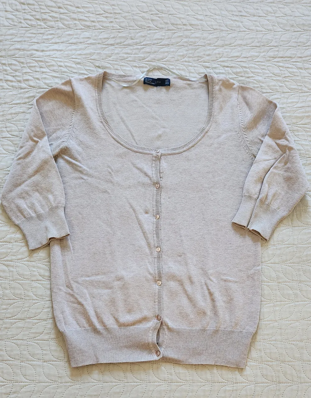 Cardigan de hilo color crudo con botones al frente y mangas 3/4.