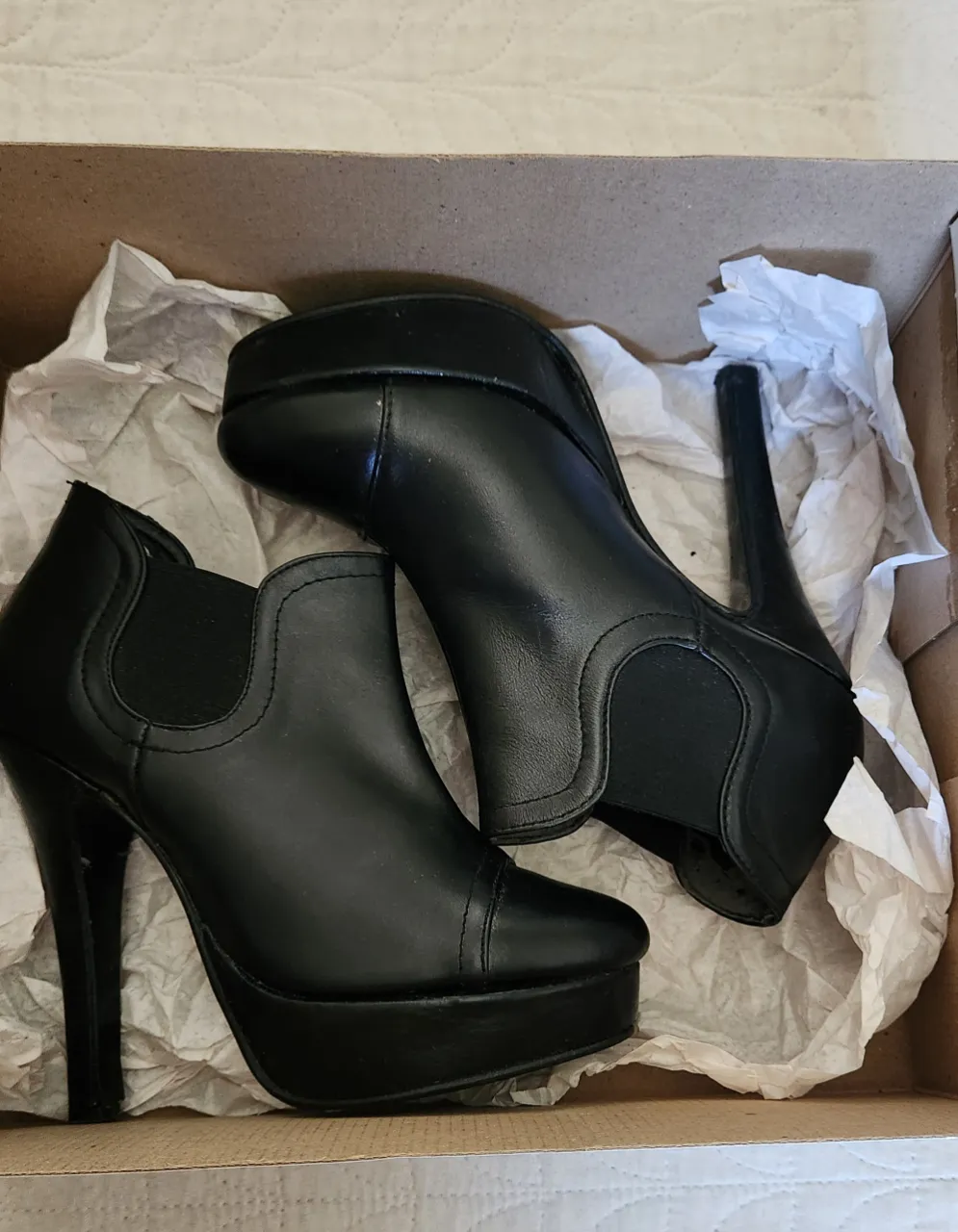 Botas negras de cuero con plataforma y taco alto. Tienen elástico a los costados para facilitar el calce.