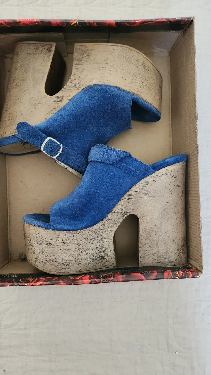 Sandalias gamuza de plataforma con taco alto y tiras de gamuza azul. La suela es de madera con un diseño desgastado.