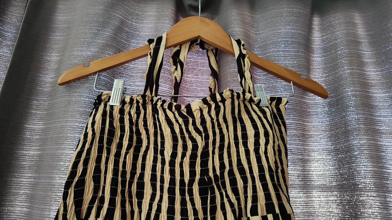 Vestido largo con estampado de rayas verticales en blanco y negro. Posee fruncido en la parte superior y tiras finas para atar en el cuello. Tiene un volado en la parte inferior.