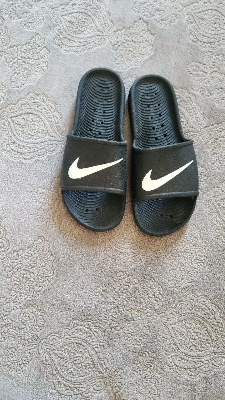 Ojotas negras de goma con logo blanco de Nike.