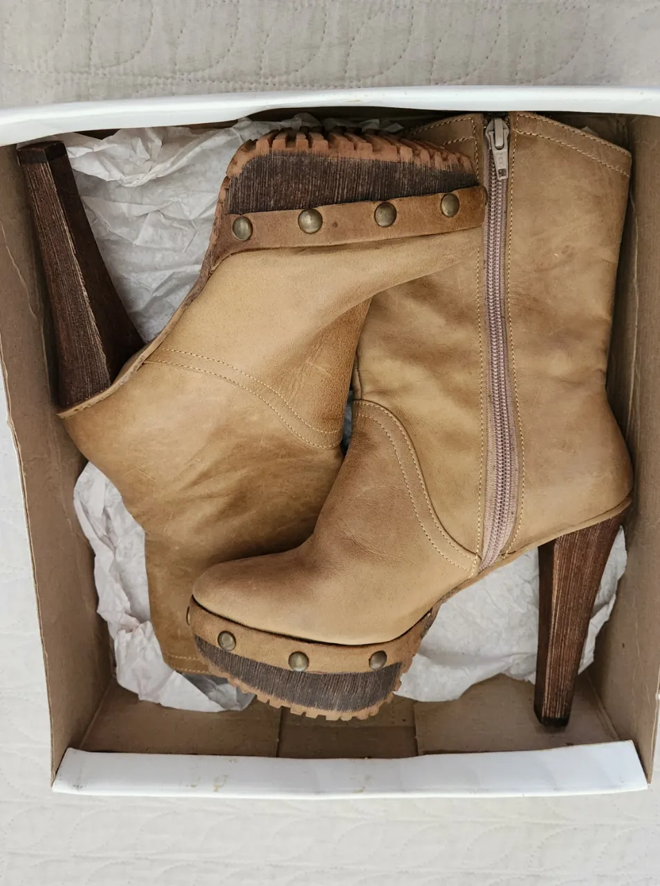 Botas de cuero color marrón con taco alto y plataforma. Cierre lateral con detalle de tachas en la suela y el borde superior.