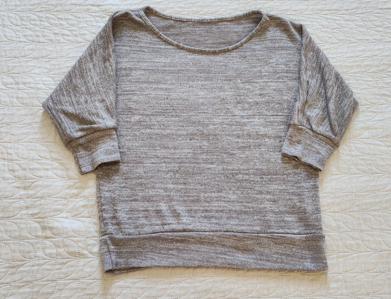 Remera gris jaspeado con detalles plateados brillantes. Mangas 3/4. Cuello redondo.