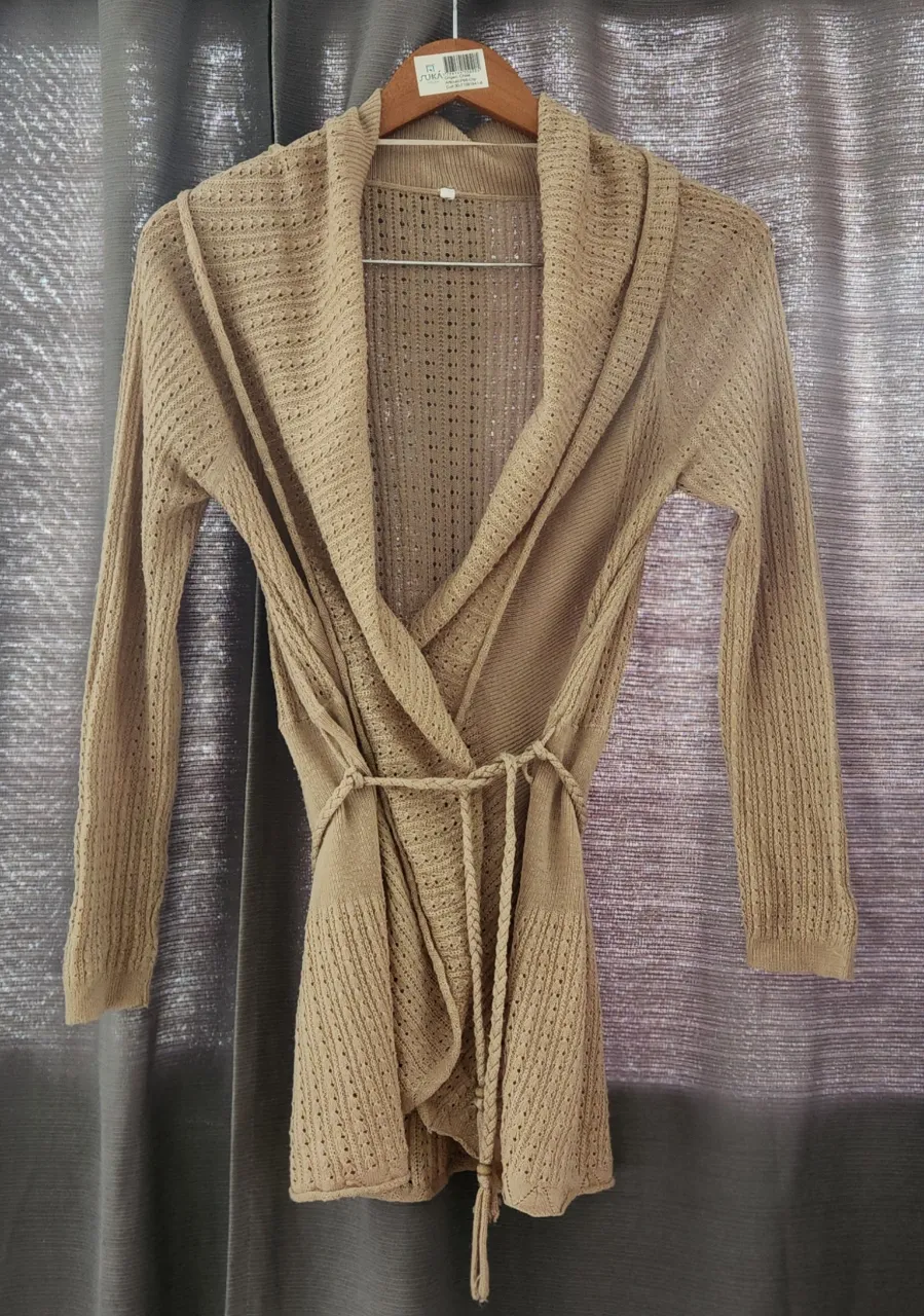 Saco tejido color tiza con cinturón de la misma tela. Posee mangas largas y cuello solapa. cinturón trenzado.