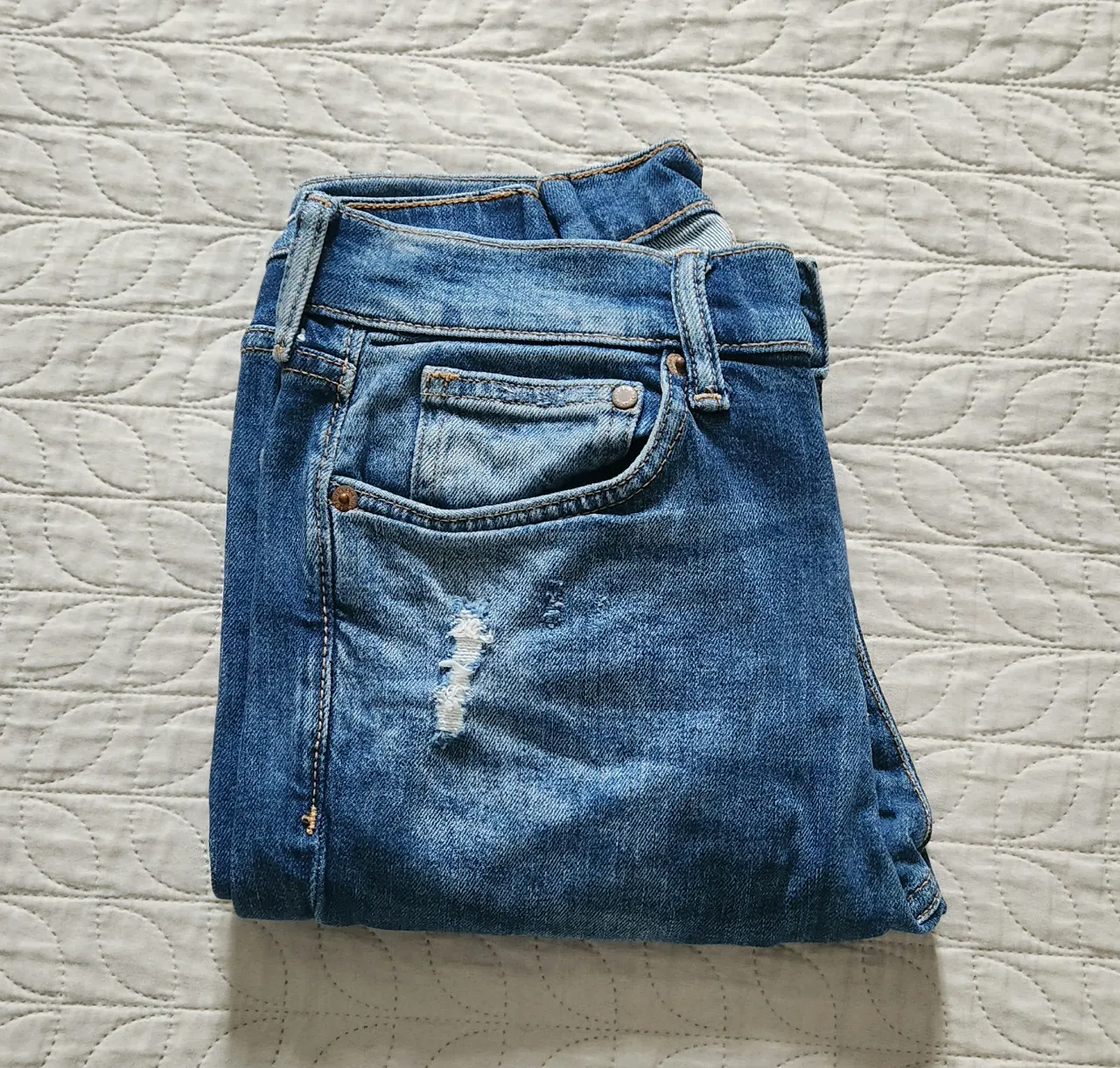 Jeans de algodón con roturas y desgaste. Cierre de botón y bolsillos frontales y traseros.