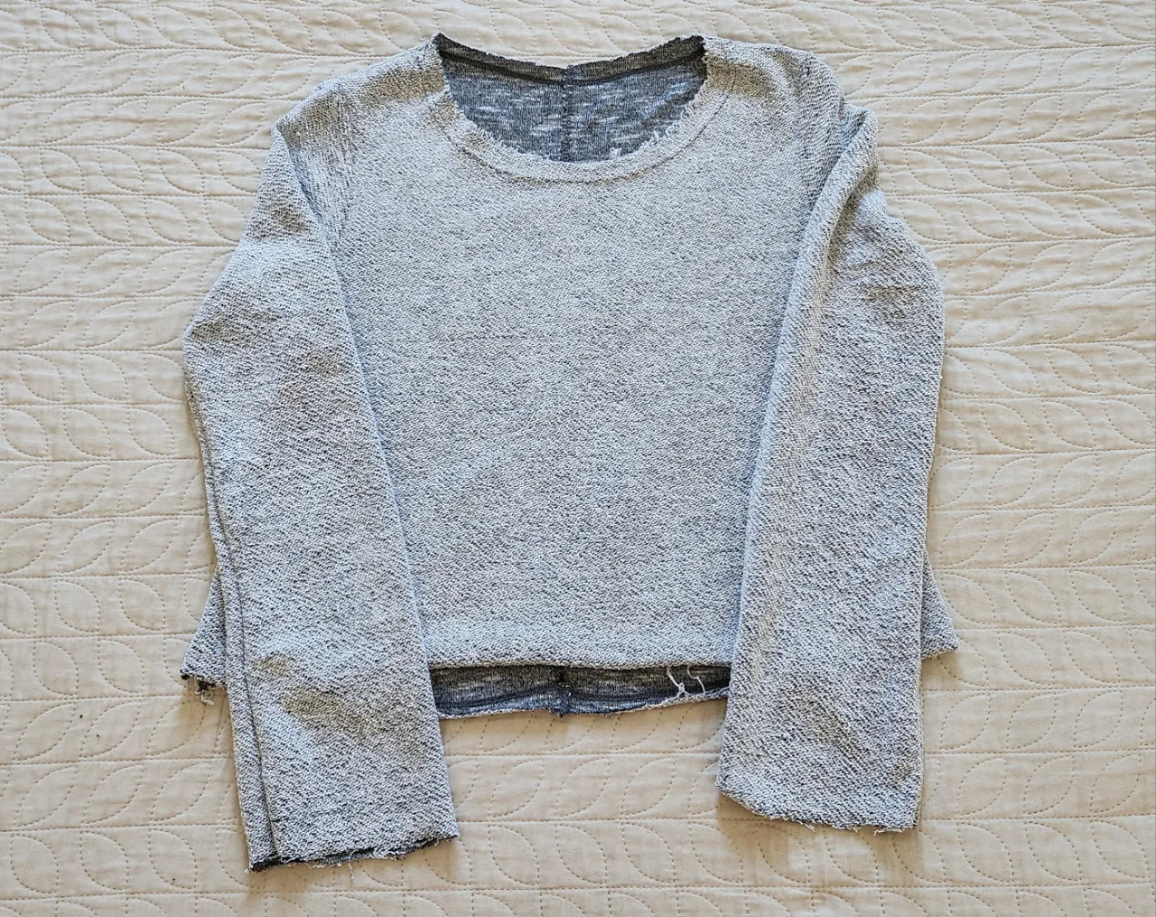 Sweater gris con cuello redondo y mangas largas. Posee detalles deshilachados en puños y ruedo.