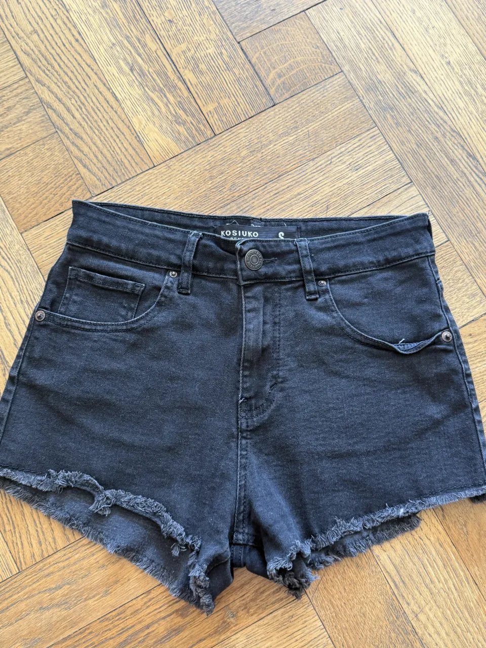 Short de jean negro lavado con roturas y flecos en el ruedo. 