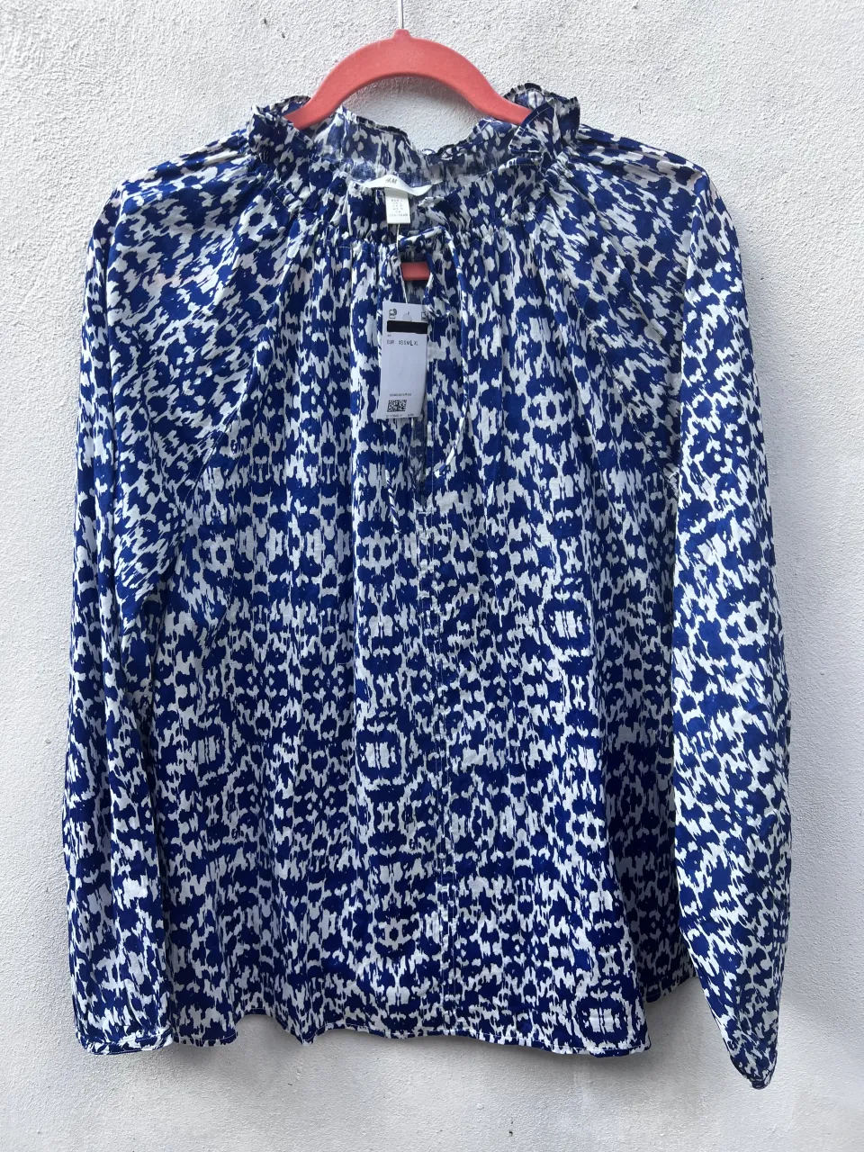 Blusa estampada con cuello redondo y detalle de volados. Manga larga con puño. Estampado abstracto en azul y blanco.