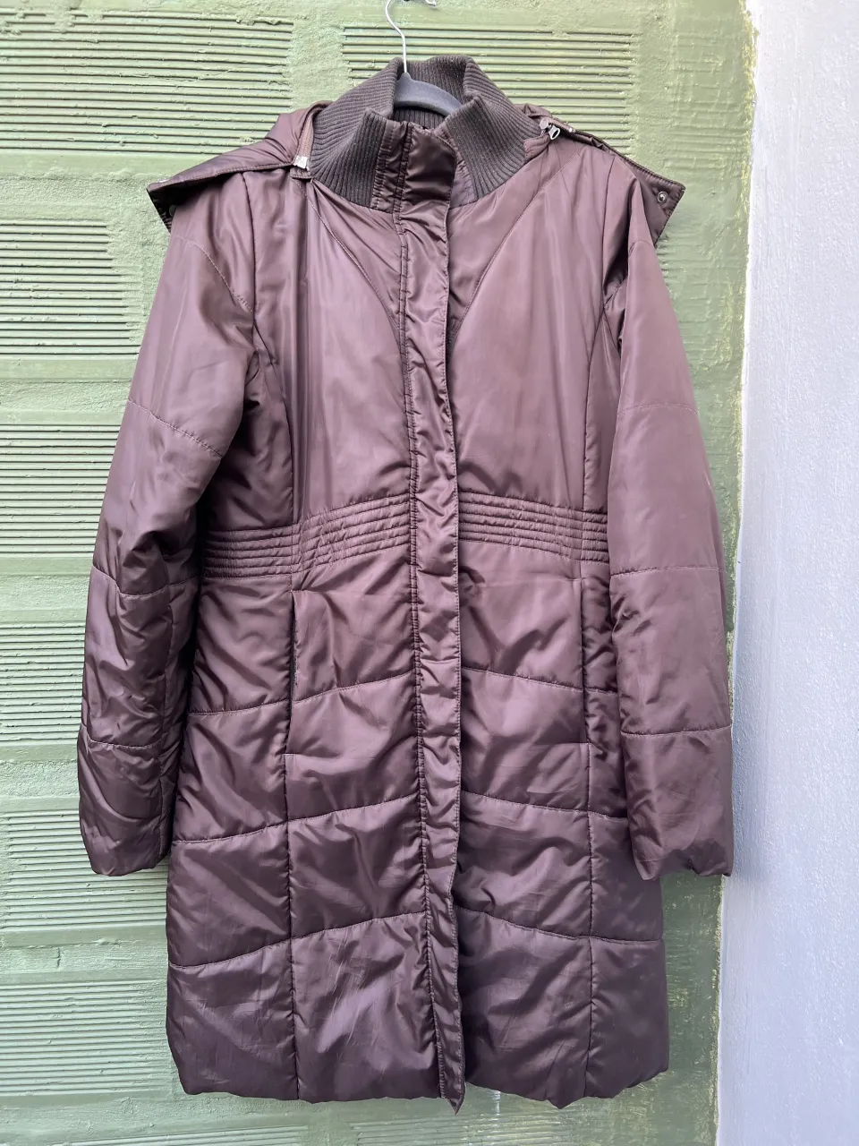 Campera larga acolchada con capucha forrada en piel sintética. Posee cuello tejido y cierre al frente. Dos bolsillos exteriores con cierre y dos bolsillos interiores.