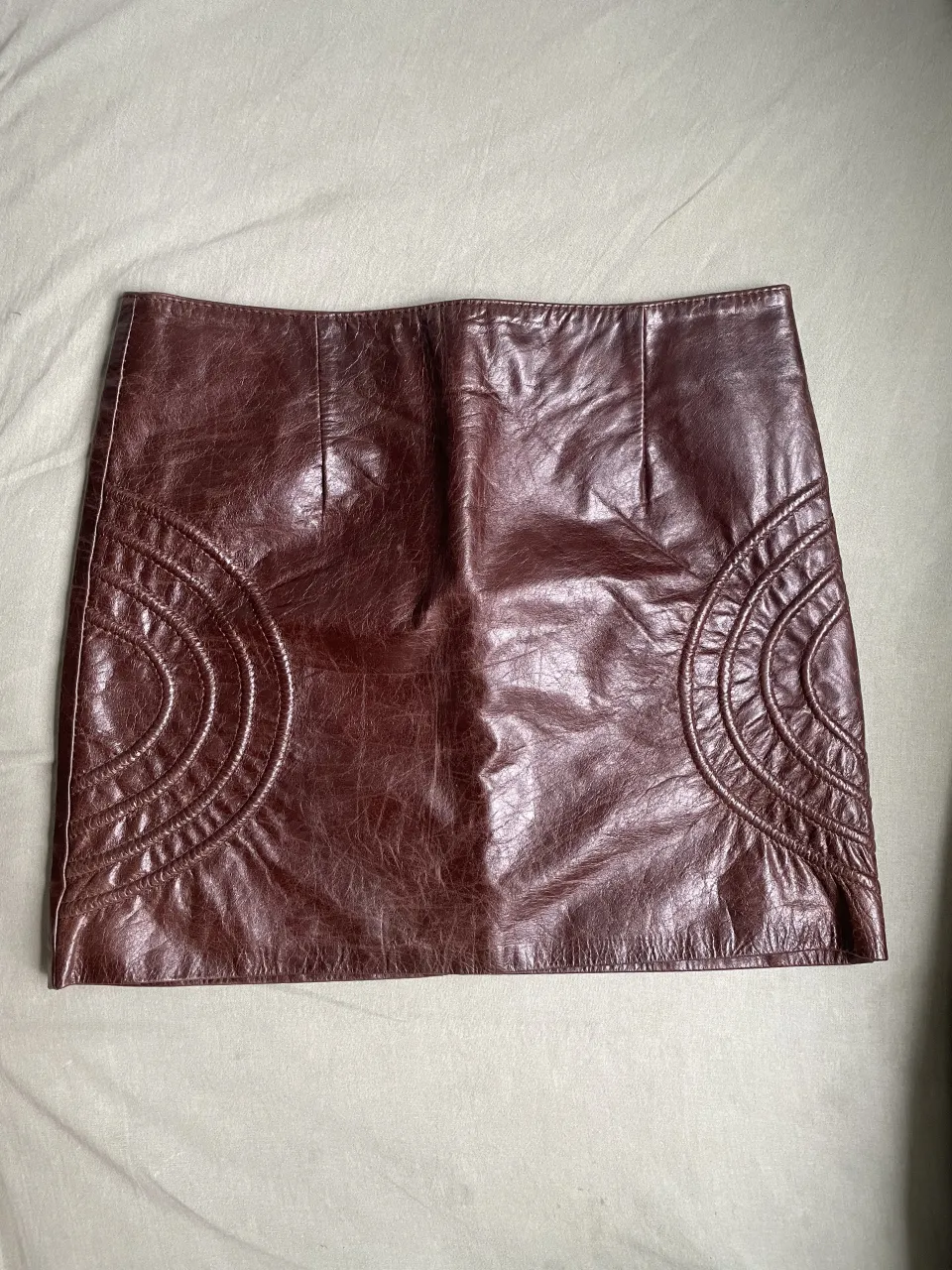 Pollera corta de cuero marrón. Posee detalles de costuras circulares en los laterales delanteros. Cierre en la espalda. MUY POCO USO