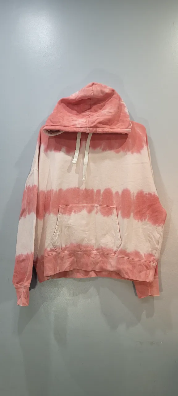 Buzo con capucha y cordones blancos. Diseño de franjas horizontales en rosa y blanco. Posee bolsillo tipo canguro al frente.