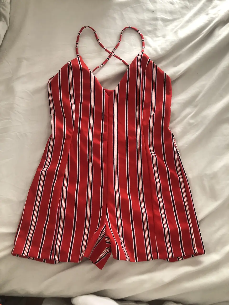 Mono corto de mujer con estampado a rayas verticales en rojo y blanco. Diseño con tirantes cruzados en la espalda y escote en V. Ideal para un look fresco y veraniego.