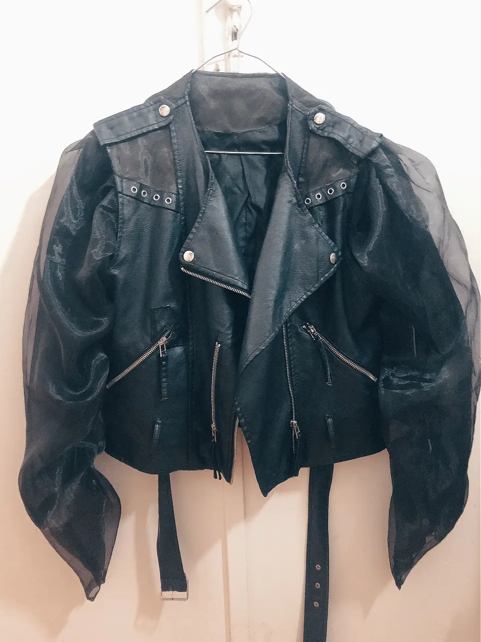 Campera biker intervenida de cuero sintético negro con mangas de micro tul y gasa. tachas en solapas y hombros. Cierre asimétrico y cinturón en la cintura. Ideal para un look rockero y audaz.