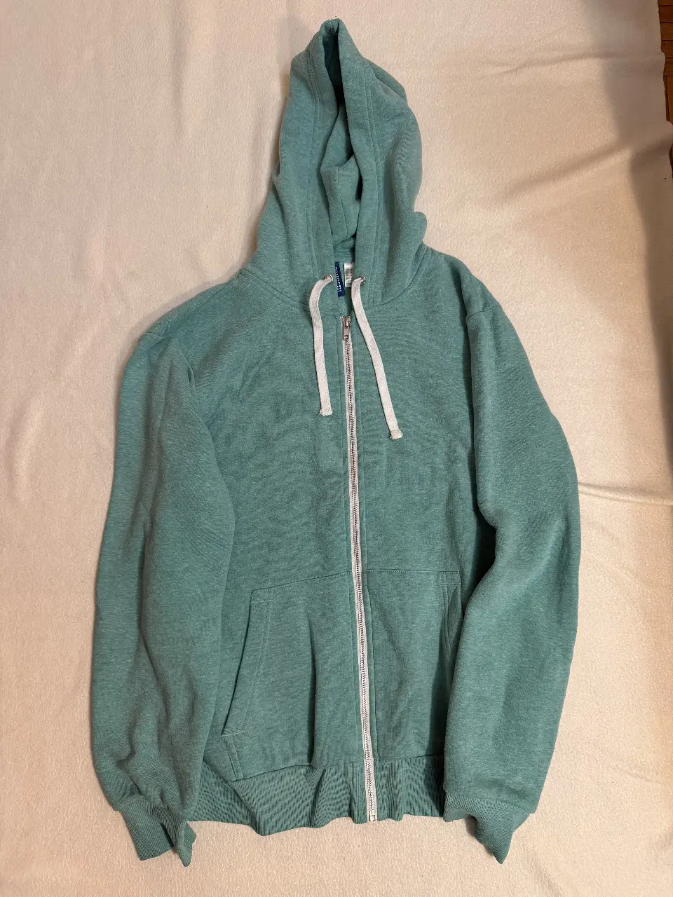 Buzo con cierre y capucha en color verde agua. Ideal para un look casual y cómodo. Perfecto para usar en cualquier momento del día.