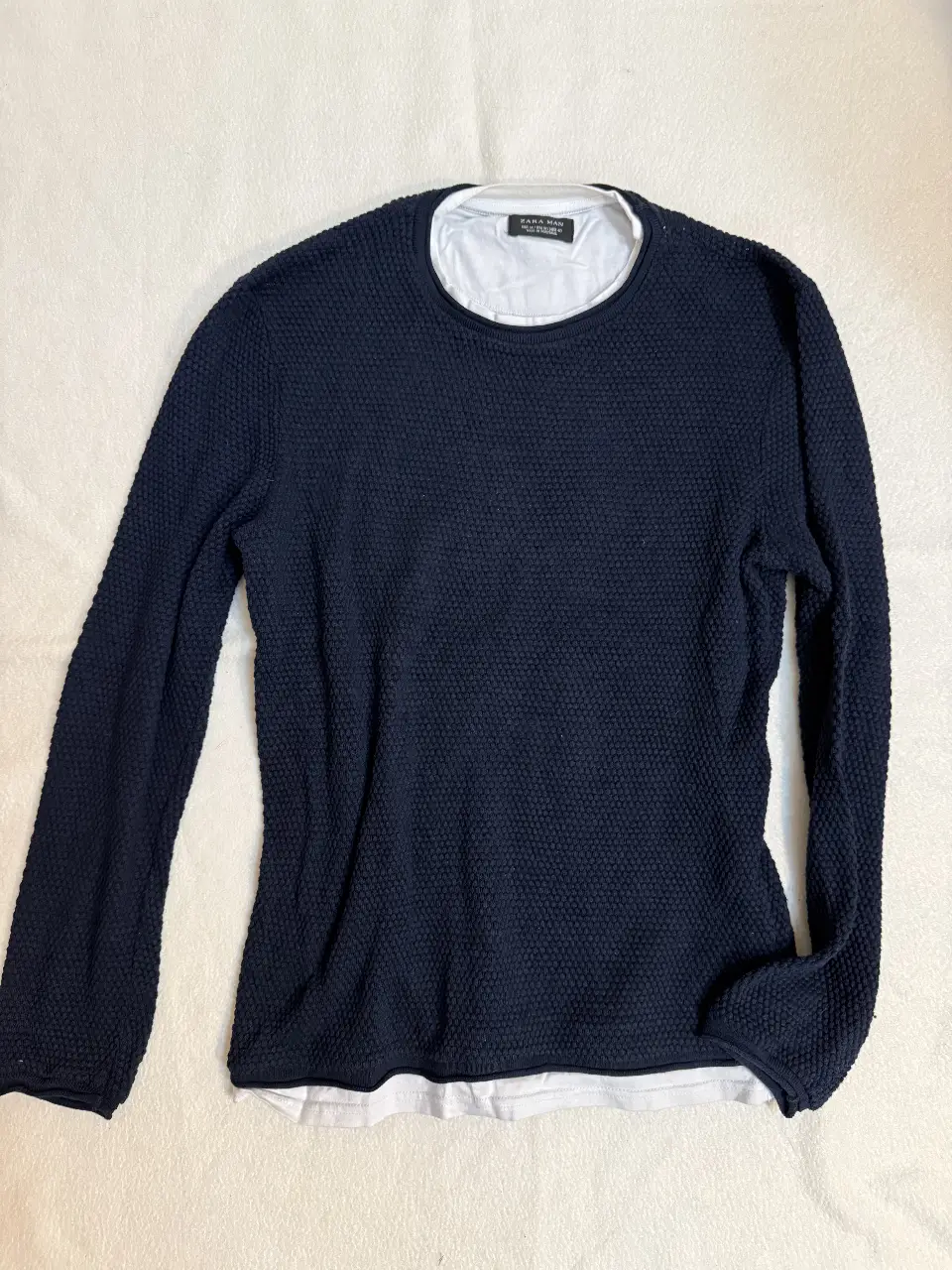 Sweater de hombre azul marino con textura, cuello redondo y manga larga. Incluye una remera blanca de cuello redondo debajo pero solo las partes visibles, creando un efecto de capas. Ideal para un look casual y moderno. Más para primavera/verano. Tiene uso.