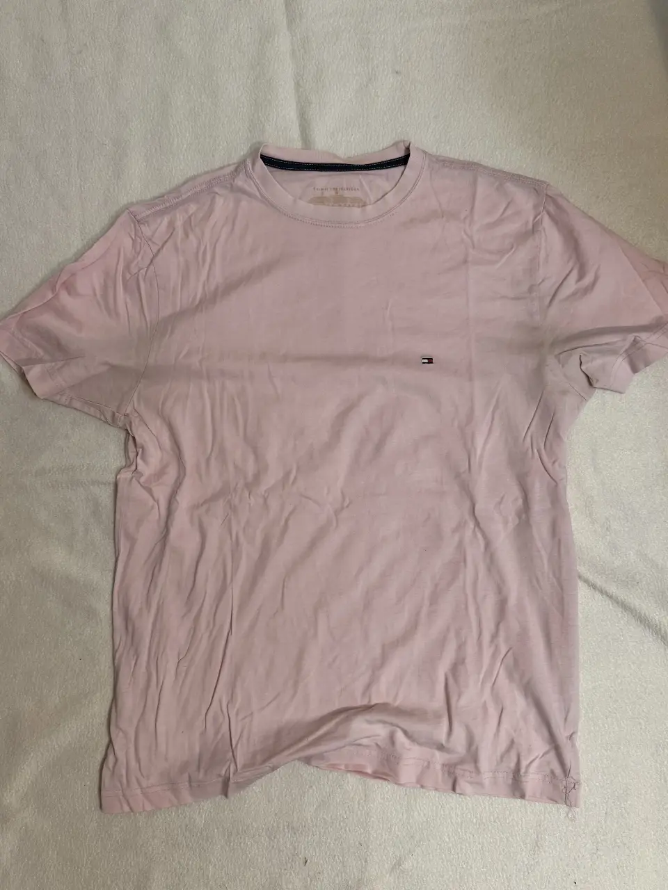 Remera Tommy Hilfiger rosa, de manga corta, con el logo de la marca bordado en el pecho. Ideal para un look casual y cómodo.