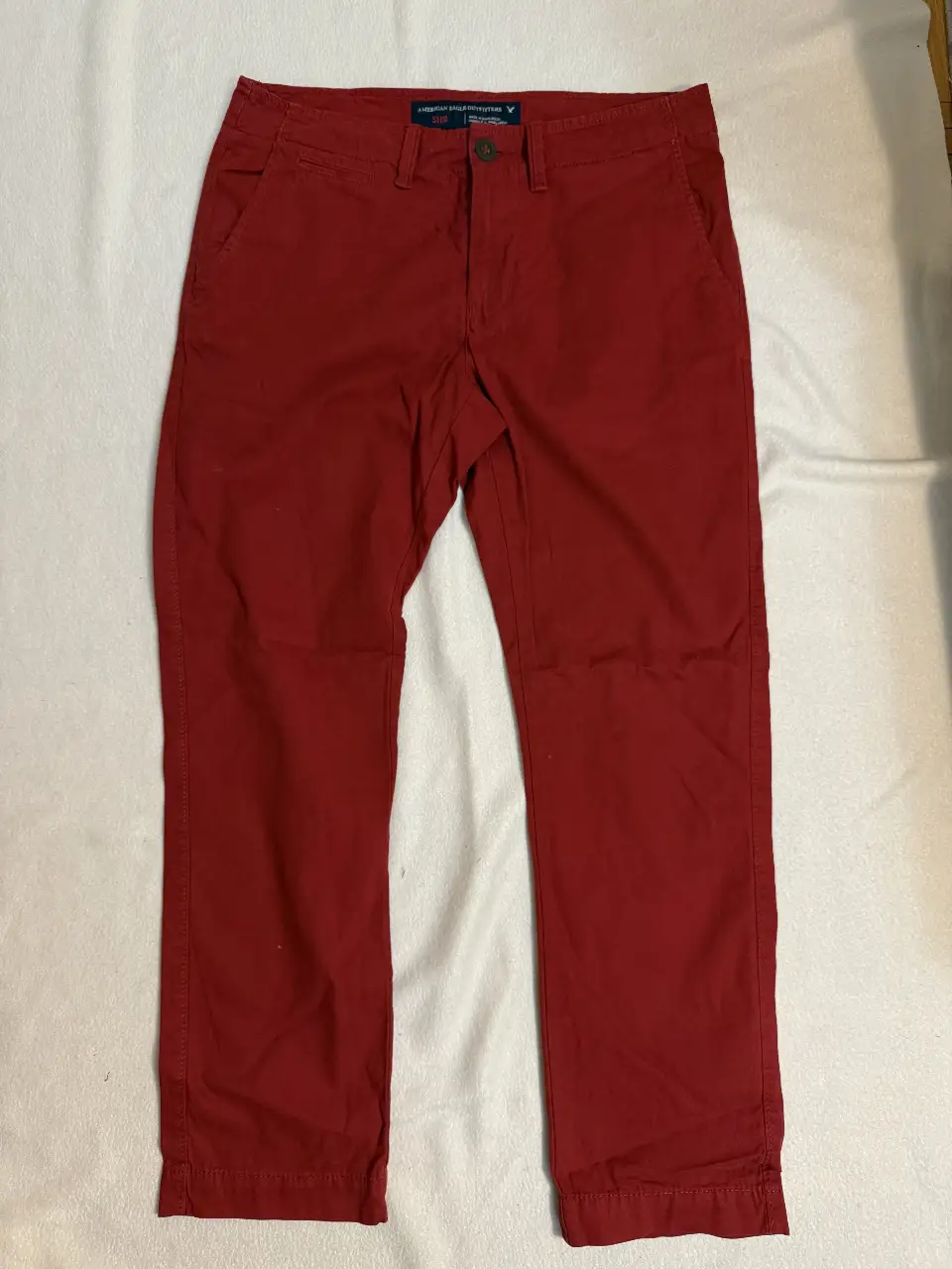 Pantalón chino rojo de hombre, corte slim, ideal para un look casual y moderno. American Eagle Outfitters.