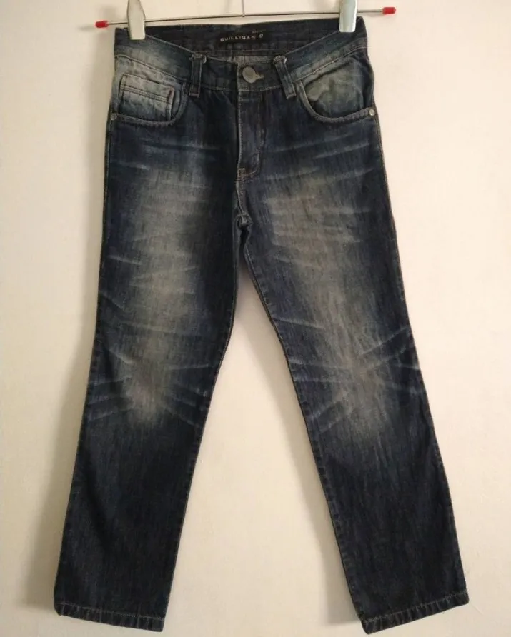 Jeans de corte clásico, con lavado desgastado y detalles de desgaste en los bolsillos y rodillas. Cierre con botón y bolsillos frontales y traseros.