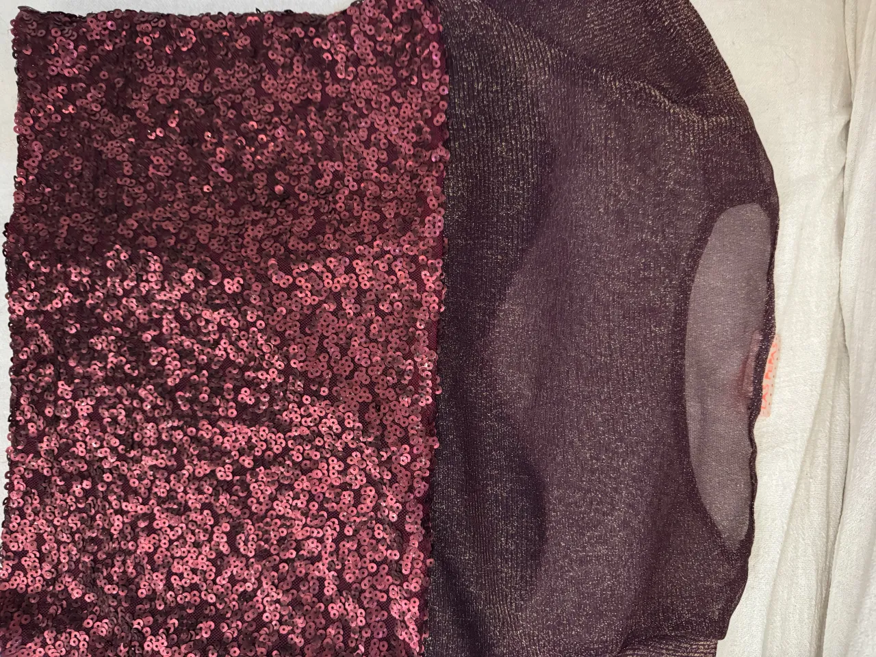 Remera con lentejuelas color bordó/vino en la parte inferior y tela metalizada transparente en la parte superior. Posee mangas cortas. Marca Las Pepas. Ideal para fiestas.