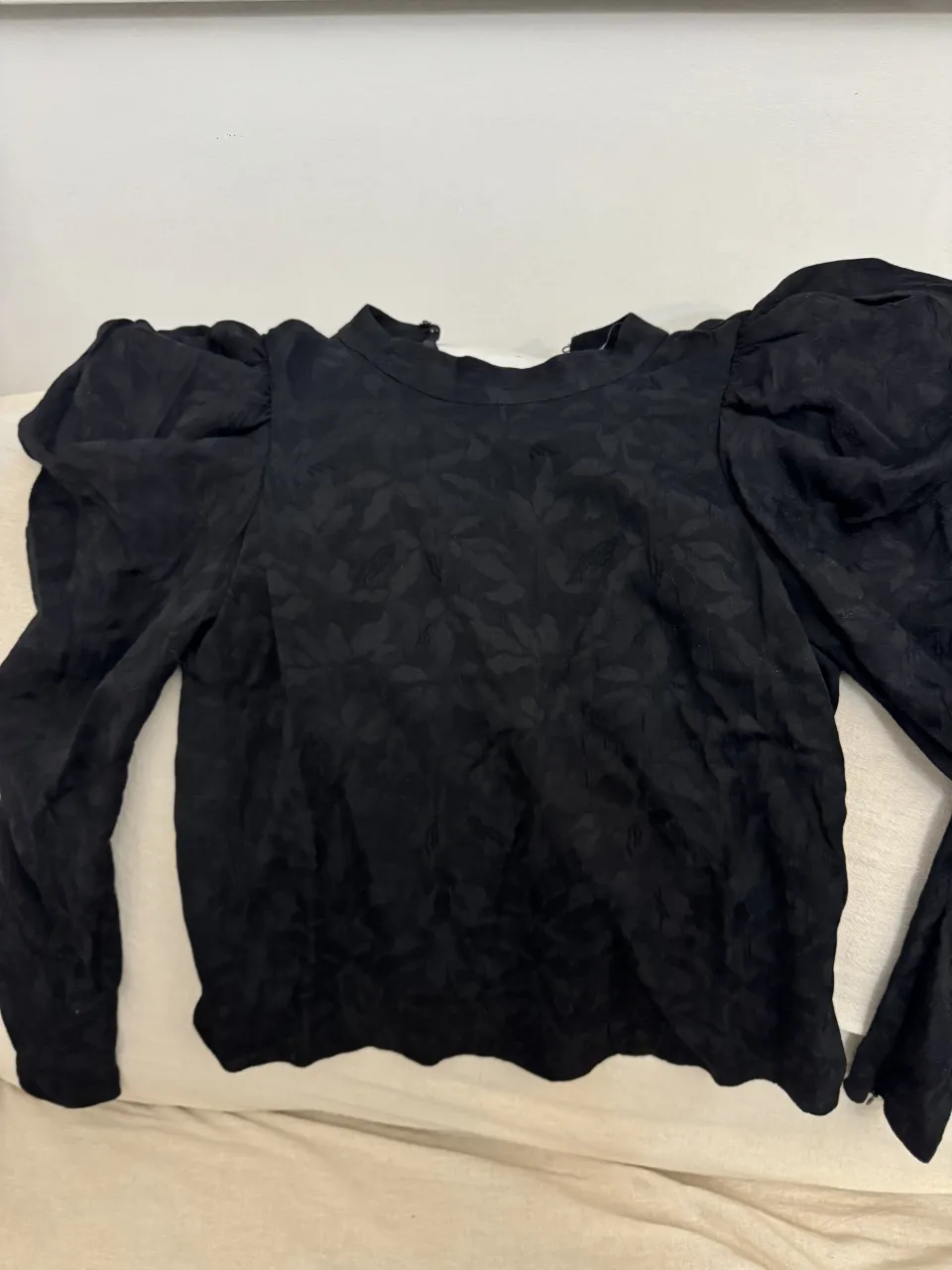 Blusa negra marca Zara con mangas largas abullonadas y textura de hojas. Cuello alto. Súper fina.