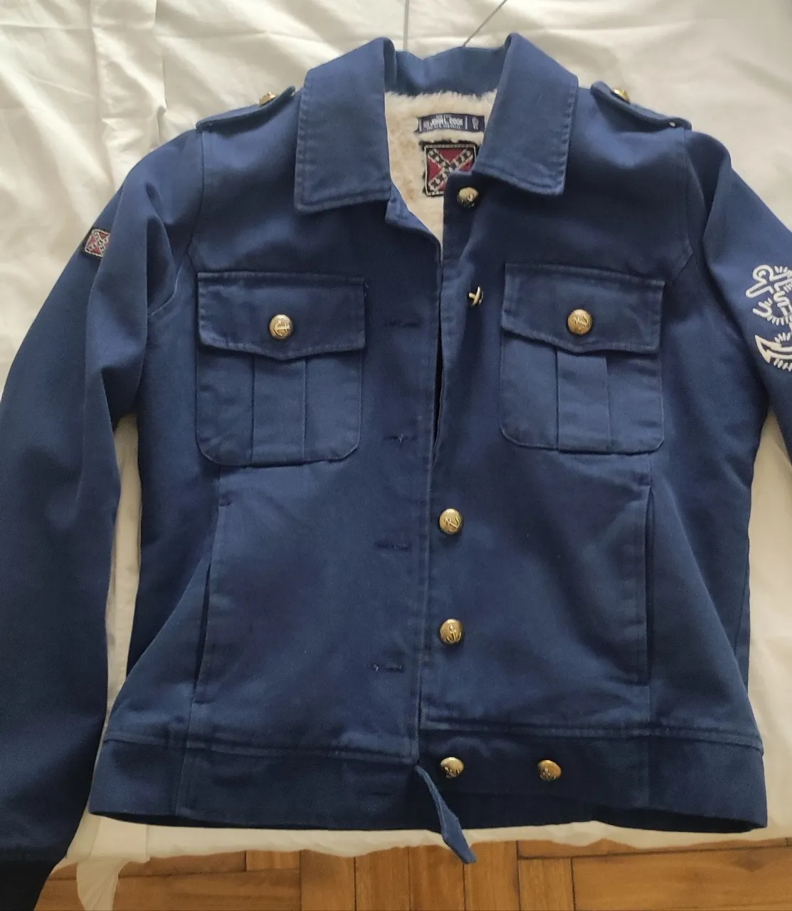Campera azul marino con forro interno de peluche, marca John L Cook, muy buena calidad. Suelo usar talle entre M y L. Ideal para un look canchero y abrigado. Posee bolsillos frontales con tapa y botones dorados, además de detalles de hombreras y un bordado en la manga. Tiene todos los botones.