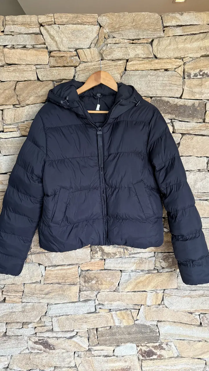 Campera de pluma negra, ideal para el invierno. Con capucha y cierre frontal. Perfecta para un look casual y abrigado.