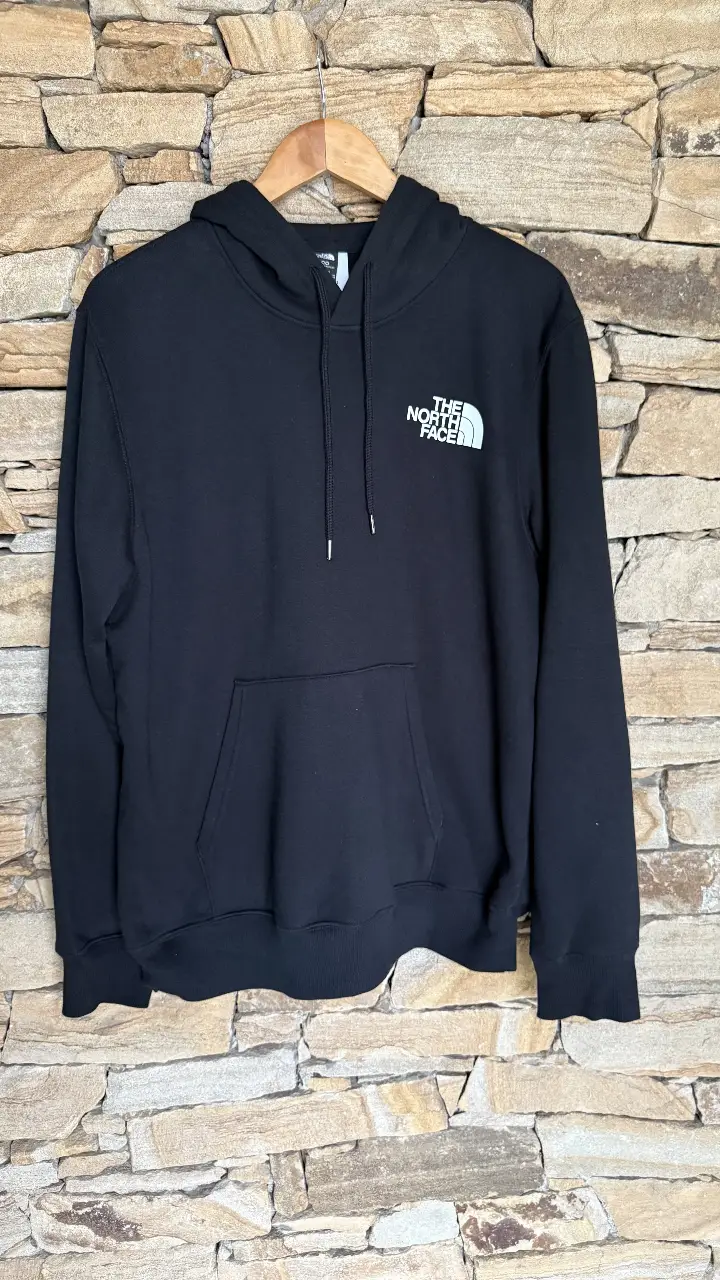 Buzo canguro negro de hombre con capucha y el logo de The North Face en blanco en el pecho. En la espalda, el logo y la frase 'Never Stop Exploring'. Ideal para un look casual y urbano.