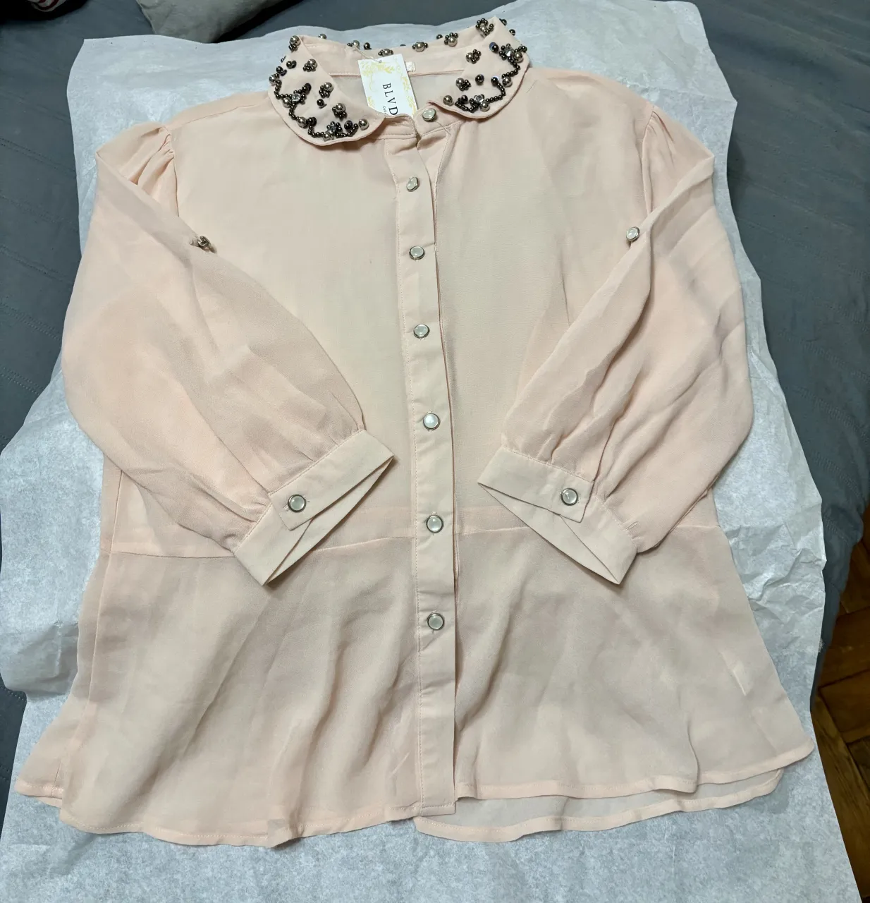 Blusa romántica color rosa pálido con cuello camisero adornado con pedrería plateada. Posee mangas largas abullonadas con puños abotonados y botones frontales perlados. con recorte en la cintura
Nueva sin uso, comprada en Uruguay ✨💫
Talle L que puede usarse como M