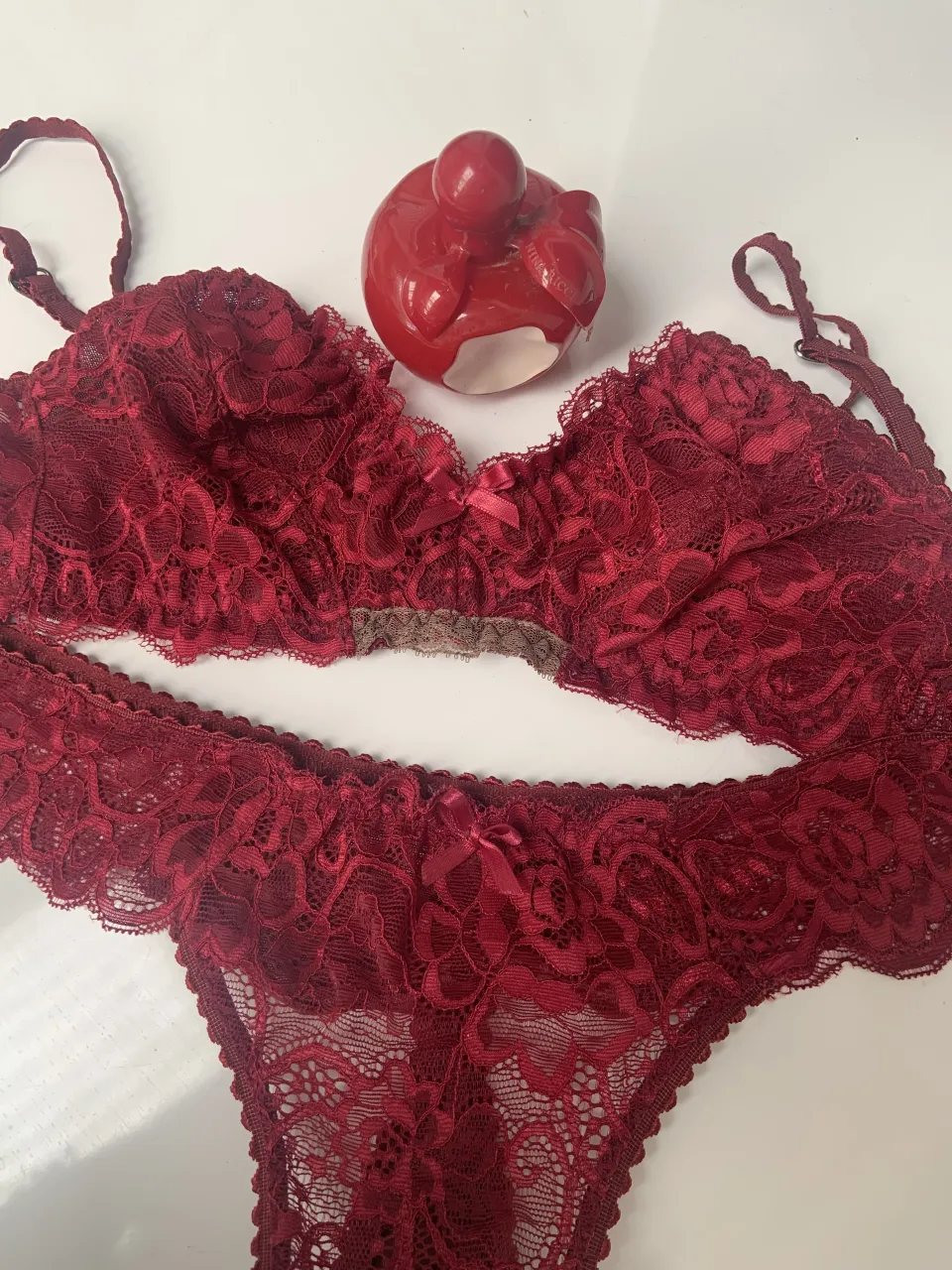 Conjunto de lencería de encaje color bordó. Incluye corpiño con tiras regulables y bombacha less. Detalle de moño en ambos conjuntos.