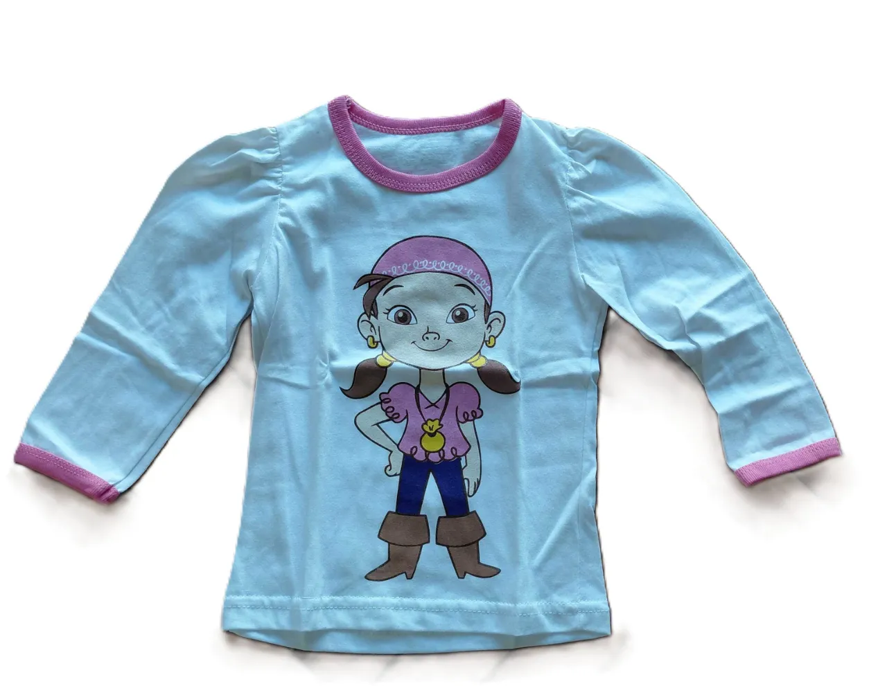 Remera manga larga celeste con estampa de personaje pirata en el frente. Cuello y puños con vivos fucsia. Detalle de costuras y etiqueta cuadrada con inscripción en la espalda.