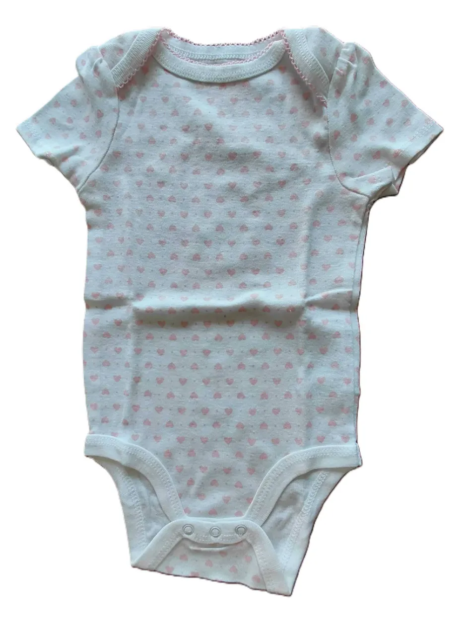 Body de bebé blanco con estampa de corazones rosas pequeños. Tiene mangas cortas y broches en la parte inferior.