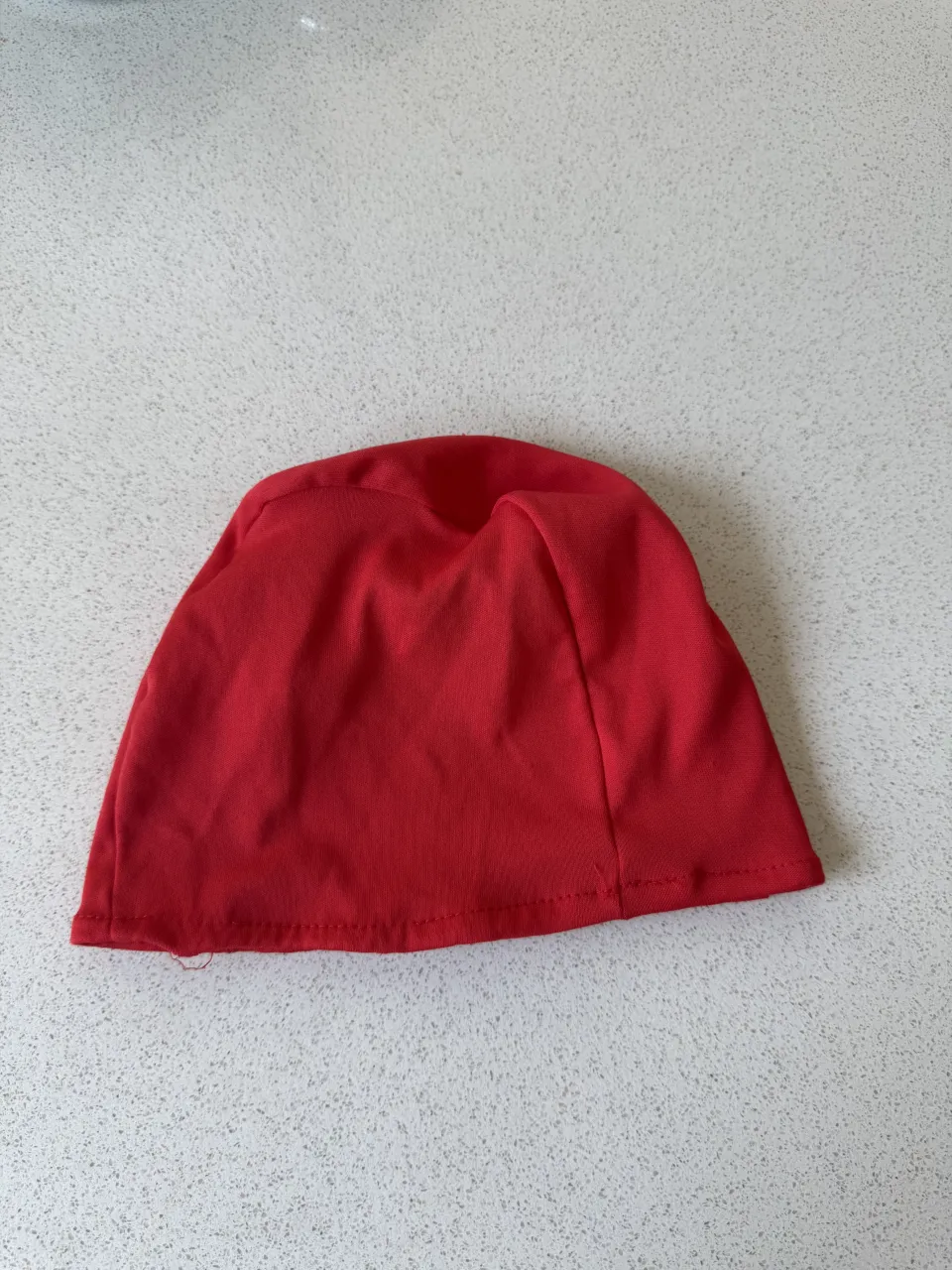 Gorro de tela rojo, ideal para protegerse del sol o del frío. Su diseño simple y elástico lo hace cómodo y adaptable.