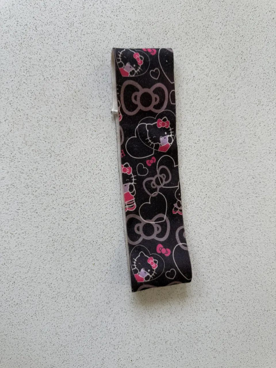 Vincha estampada con motivo de Hello Kitty y moños. Ideal para darle un toque divertido y original a tu look.