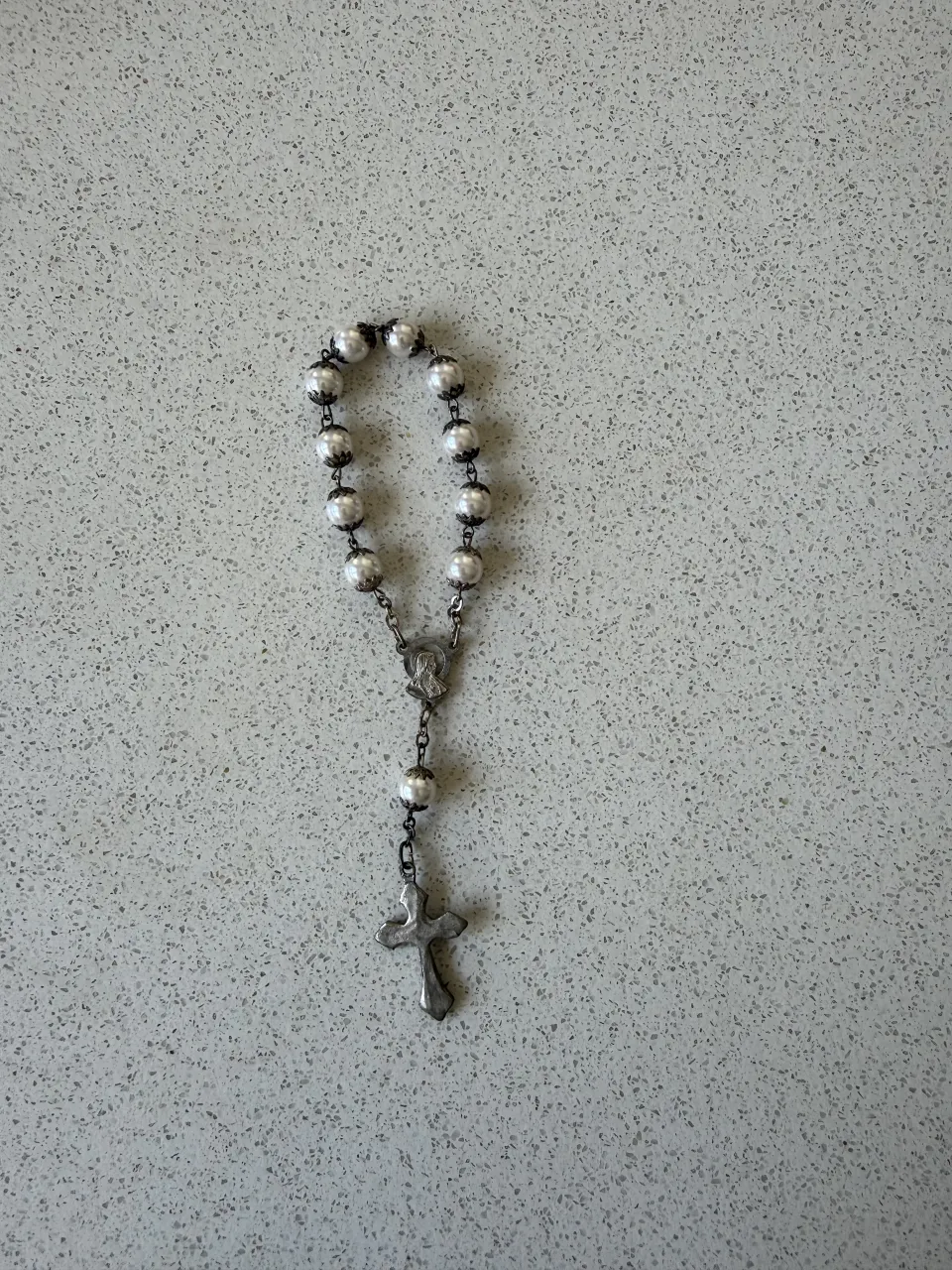 Abalorio de plata con cuentas plateadas y cruz colgante. Ideal para complementar tu look.