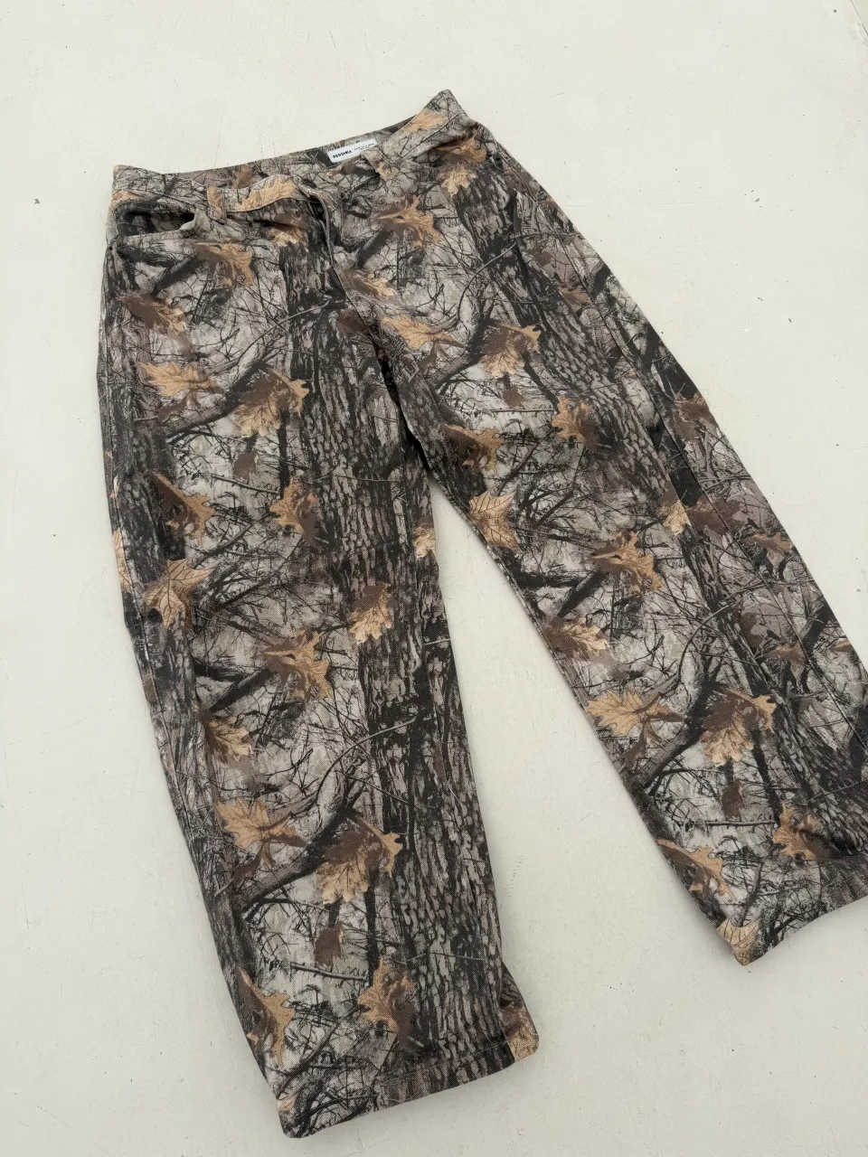 Pantalón estampado camuflado de árboles y hojas.